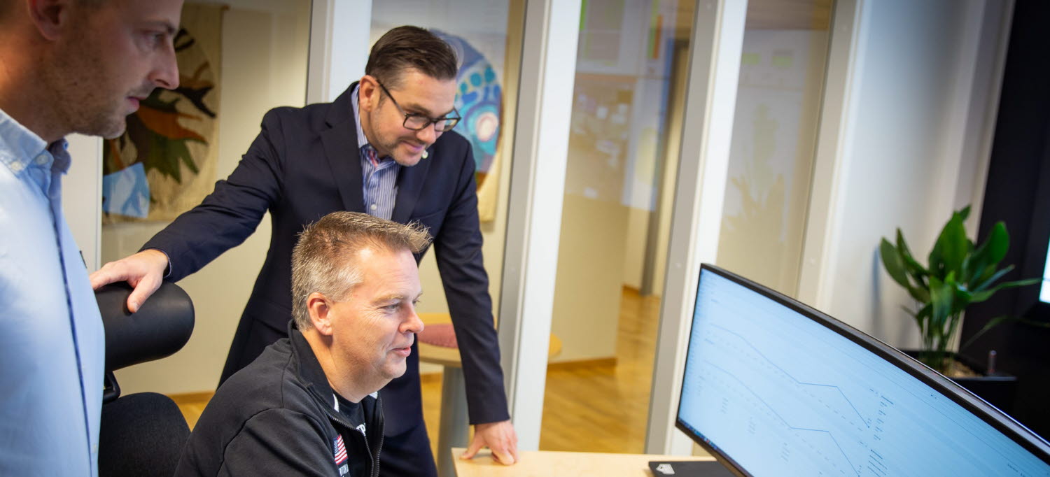Tre medarbetare på IT-förvaltningen står vid en datorskärm.
