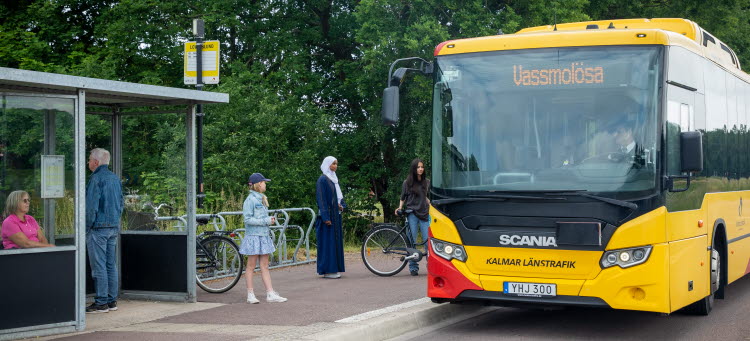 Resenärer vid en busshållplats samtidigt som en buss stannar.