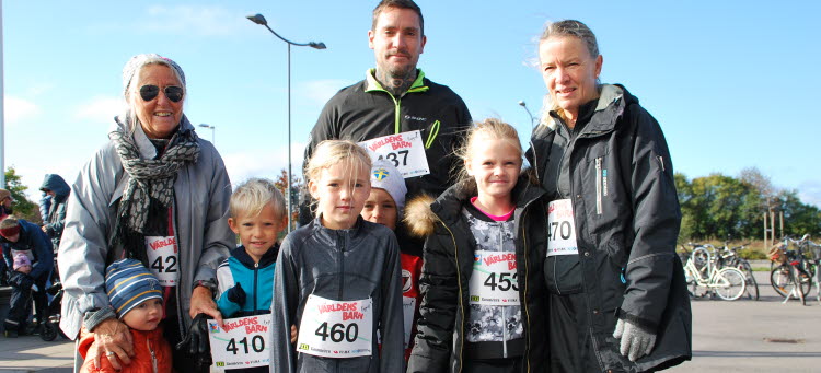 Åtta personer i olika åldrar med nummerlappar för Världens barnloppet på magen.