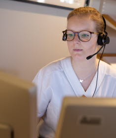 En kvinna med headset vid en dator