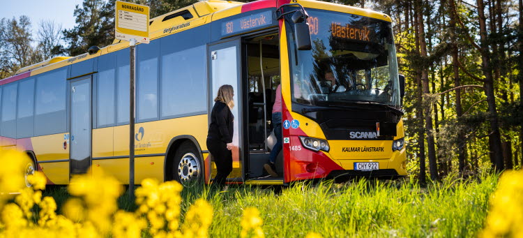 Gul och röd buss som stannat för att släppa på en passagerare.