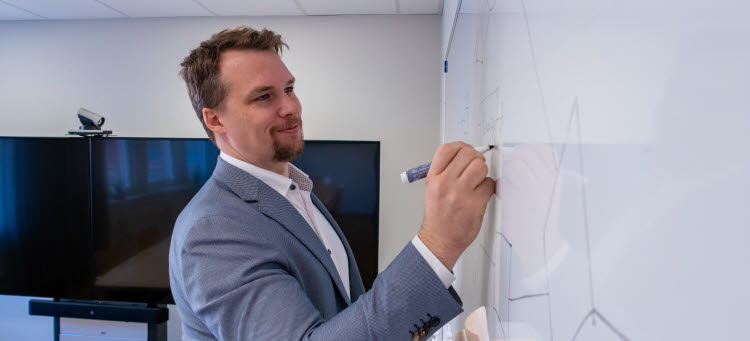 Stefan Åberg ler och skriver på en whiteboard