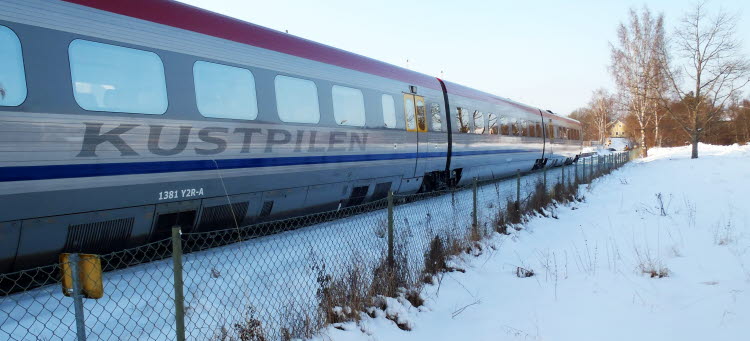 Kustpilen tåg på väg i snöigt landskap