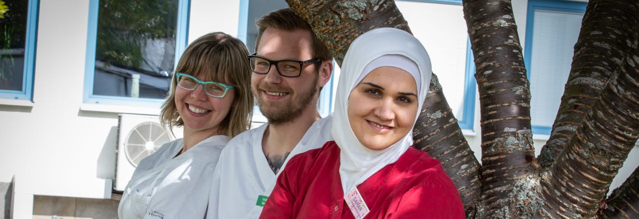 Tre leende kollegor som tittar mot fotografen.