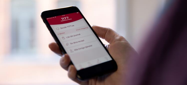Hand som håller i en mobiltelefon som visar 1177 i överkant.