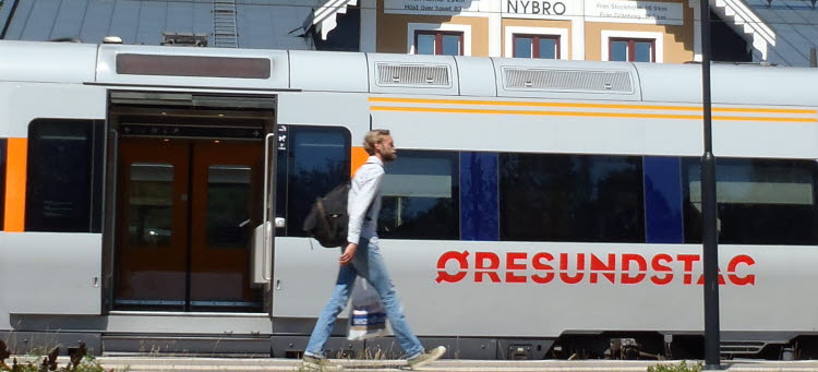 En man går framför ett Öresundståg vid stationen i Nybro.