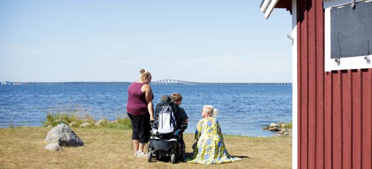 Tre kvinnor tittar ut över ett sommarlandskap vid Kalmarsund och Ölandsbron.