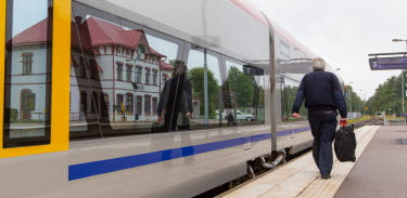En man går med ryggen mot kameran där ett tåg står parkerat på stationen i Berga.