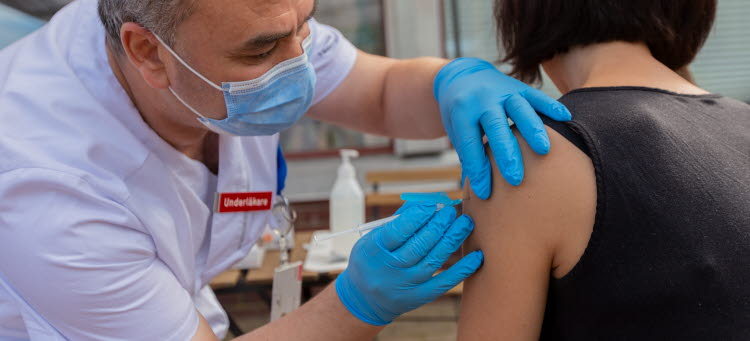 En man ger en en kvinna vaccin i överarmen.