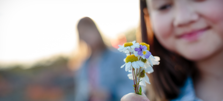 En flicka håller i några små blommor.