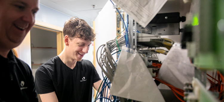 Två personer, en ung och en äldre, vid en härva av sladdar.